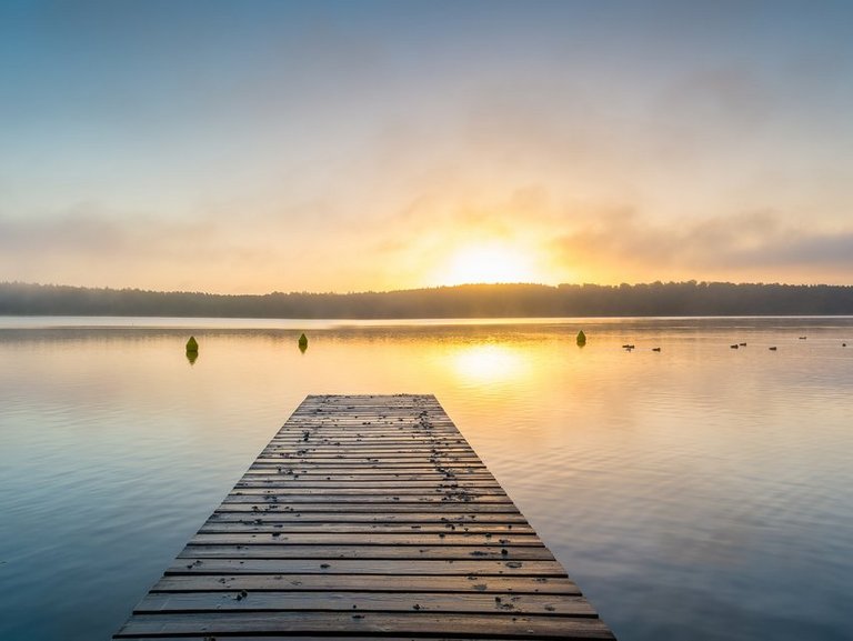 naturbild-seestimmung mit steg-sonnenspiegelung auf dem wasser